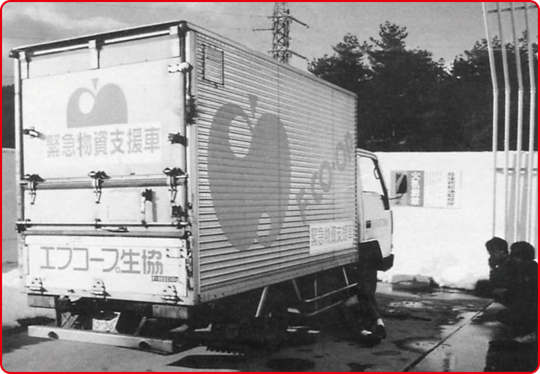 緊急物資支援車と書かれたトラックの白黒写真